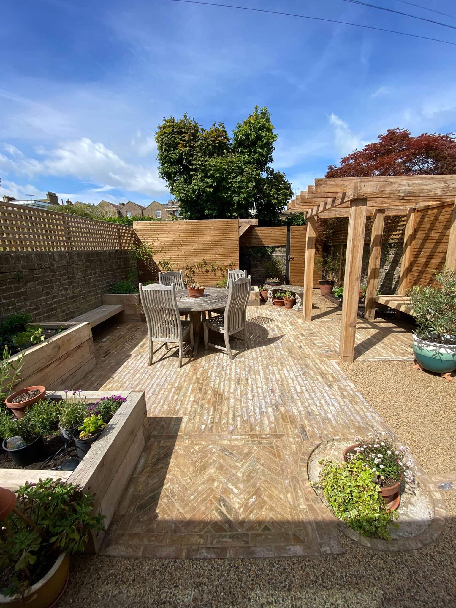 Herringbone clay-paver patio with a teak dining set beneath an oak pergola